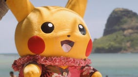 Pikachu mascot on a Hawaiian beach wearing a floral print red shirt and a lei